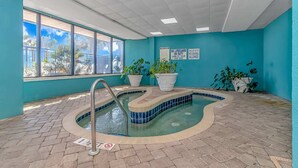 Un espace piscine doté d’un sol carrelé, d’une échelle en métal et de plantes en pot.