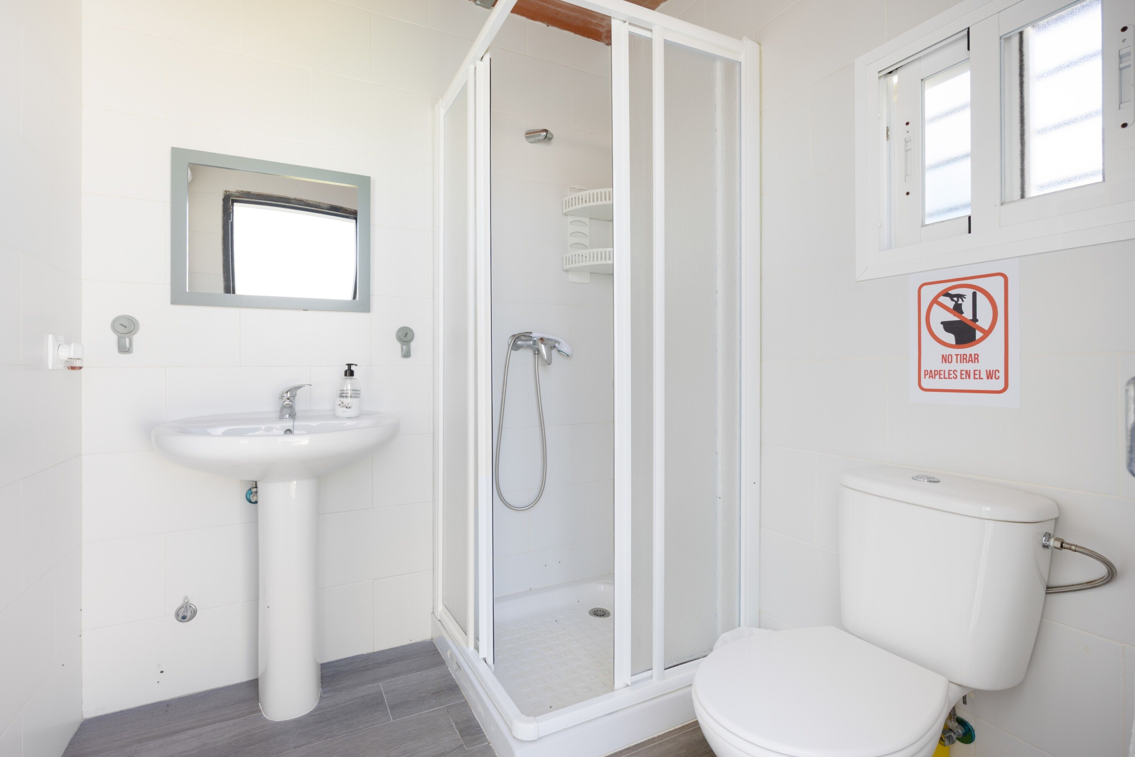 A bathroom with a white sink, toilet, and glass-enclosed shower.