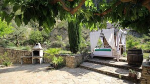 A stone patio with a barbecue grill, a bed with a canopy, and a barrel. - Country house at Le Barroux, Mont-Ventoux, air-conditioning, pets allowed (1) (LE BARROUX)
