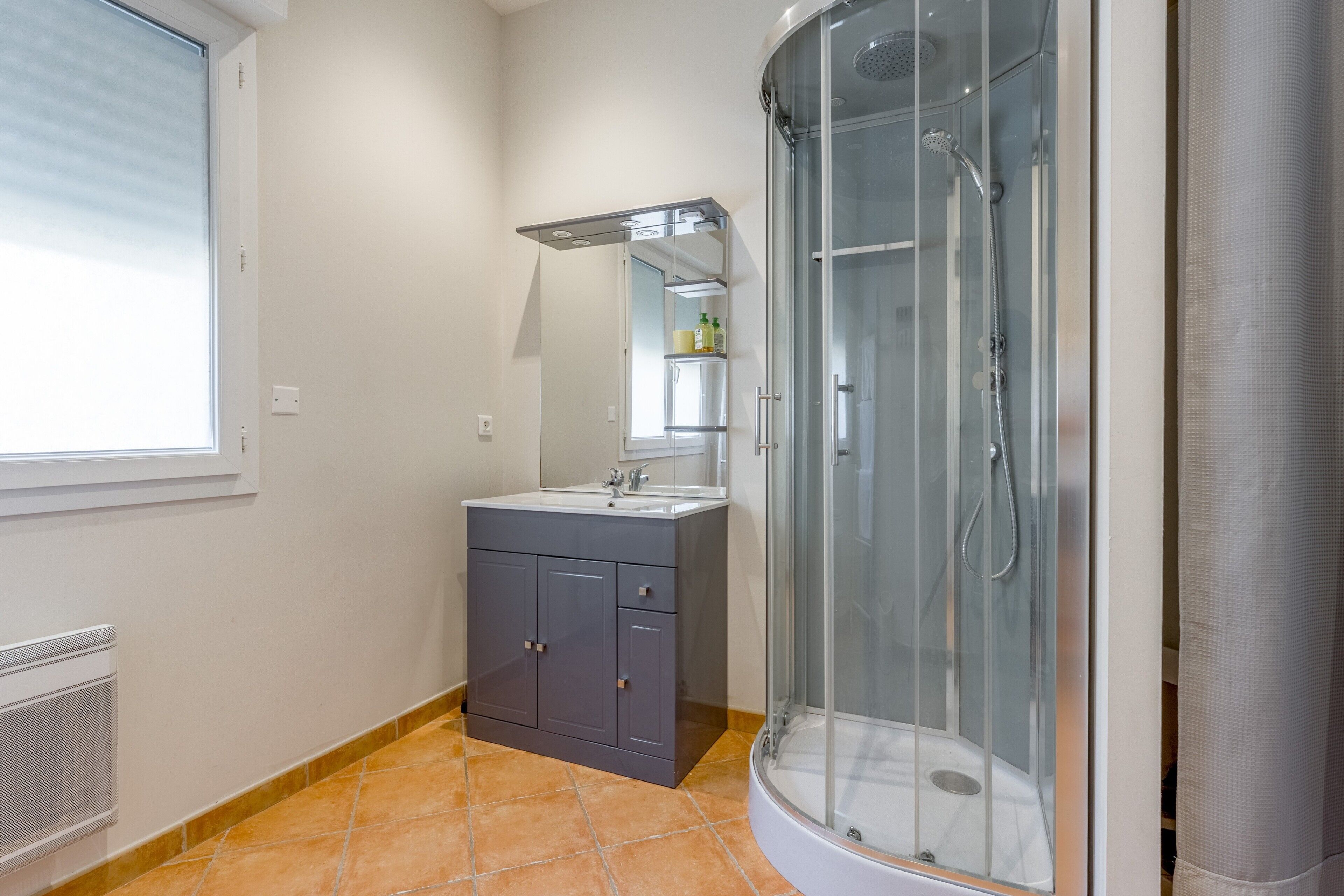 Un baño con ducha, lavamanos y armario.