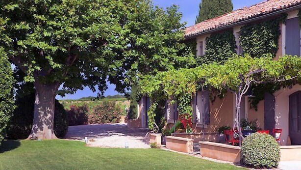 A villa with a well-maintained lawn, large trees, and a tiled roof. - In Violès, Vaucluse, exceptional vacation home, air-conditioned, heated pool. (VIOLÈS)