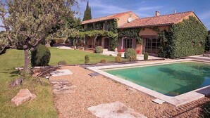 A house with a swimming pool, surrounded by a well-maintained lawn and garden. - In Violès, Vaucluse, exceptional vacation home, air-conditioned, heated pool. (VIOLÈS)