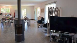 Un salon moderne doté d’un grand téléviseur, d’une cheminée et d’un coin repas avec des chaises et une table.