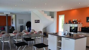 Une cuisine moderne avec des meubles blancs, un îlot central et un coin repas comprenant des chaises et des tables.