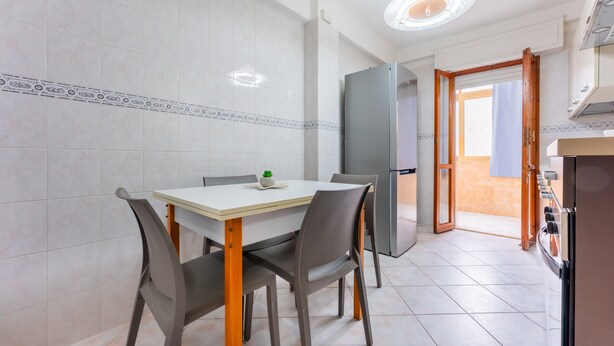 A modern kitchen with a dining area, a refrigerator, and a view to the outside.