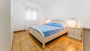 A bedroom with a bed, nightstands, and a lamp.