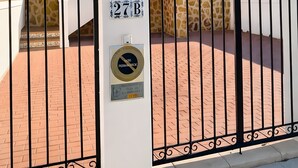 A gated entrance with a number plaque, a paved pathway, and a building with a tiled roof in the background. - Holiday Home 'Relax Inn' with Sea View, Shared Pool & Wi-Fi (Pilar de la Horadada)