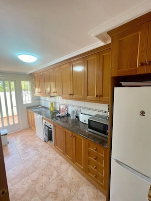 Una cocina con armarios de madera, un refrigerador blanco, un microondas y un lavavajillas.