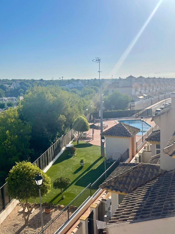 A residential area with a swimming pool, a fenced garden, and a clear view of the surrounding neighborhood.