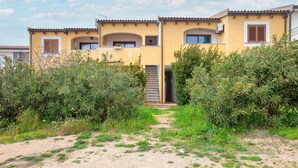 A yellow building with a staircase leading to a door, surrounded by greenery. - Apartment '8 S' with Private Terrace and Garden (Isola Rossa)