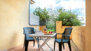 A small outdoor patio with a table and two chairs, a bowl of fruit, and a metal gate. - Apartment '8 S' with Private Terrace and Garden (Isola Rossa)