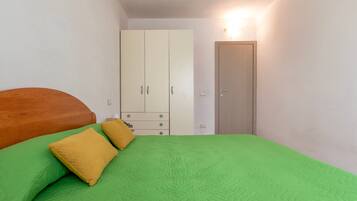 Une chambre à coucher avec un lit, une literie verte, une armoire et une porte.