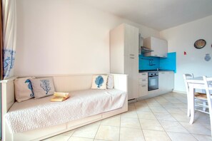 Ett kompakt bostadsutrymme med en soffa, ett litet köksområde och ett matbord.