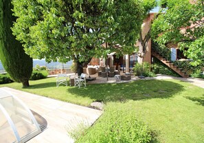 Relax in a serene outdoor space with seating areas, a shaded tree, and a staircase leading to upper levels.
