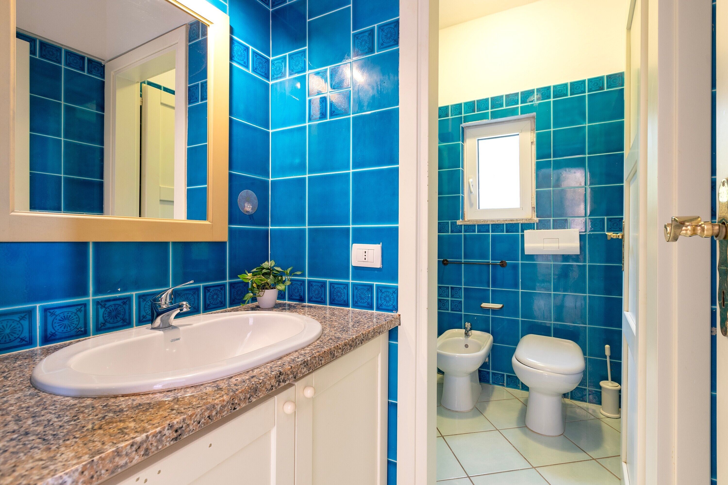 A bathroom with a sink, mirror, and blue tiled walls.