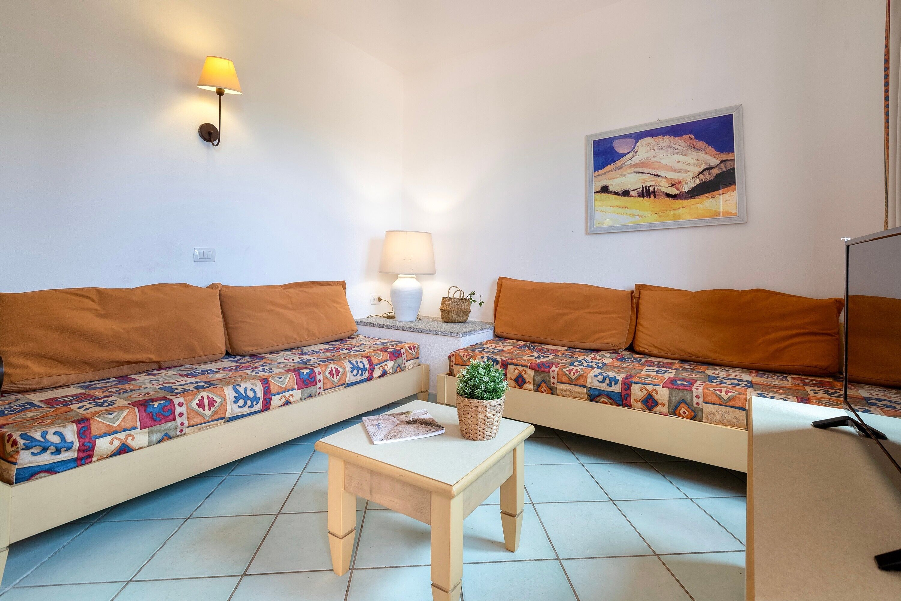 A room with two sofas, a small table, a lamp, and a painting on the wall.