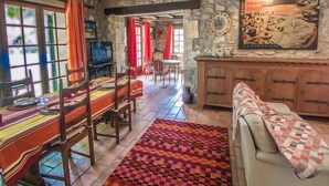 A dining area with a table set for four, a sofa, and a patterned rug. - Beautiful land house in Noves near Avignon, private pool, pets allowed (1). (NOVES)