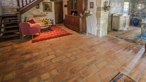 A rustic interior with exposed wooden beams, a brick floor, a wooden staircase, a sofa, a cabinet, and a vase with flowers. - Beautiful land house in Noves near Avignon, private pool, pets allowed (1). (NOVES)