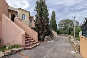A residential property with a staircase leading to a door, a stone wall, and a street lamp.