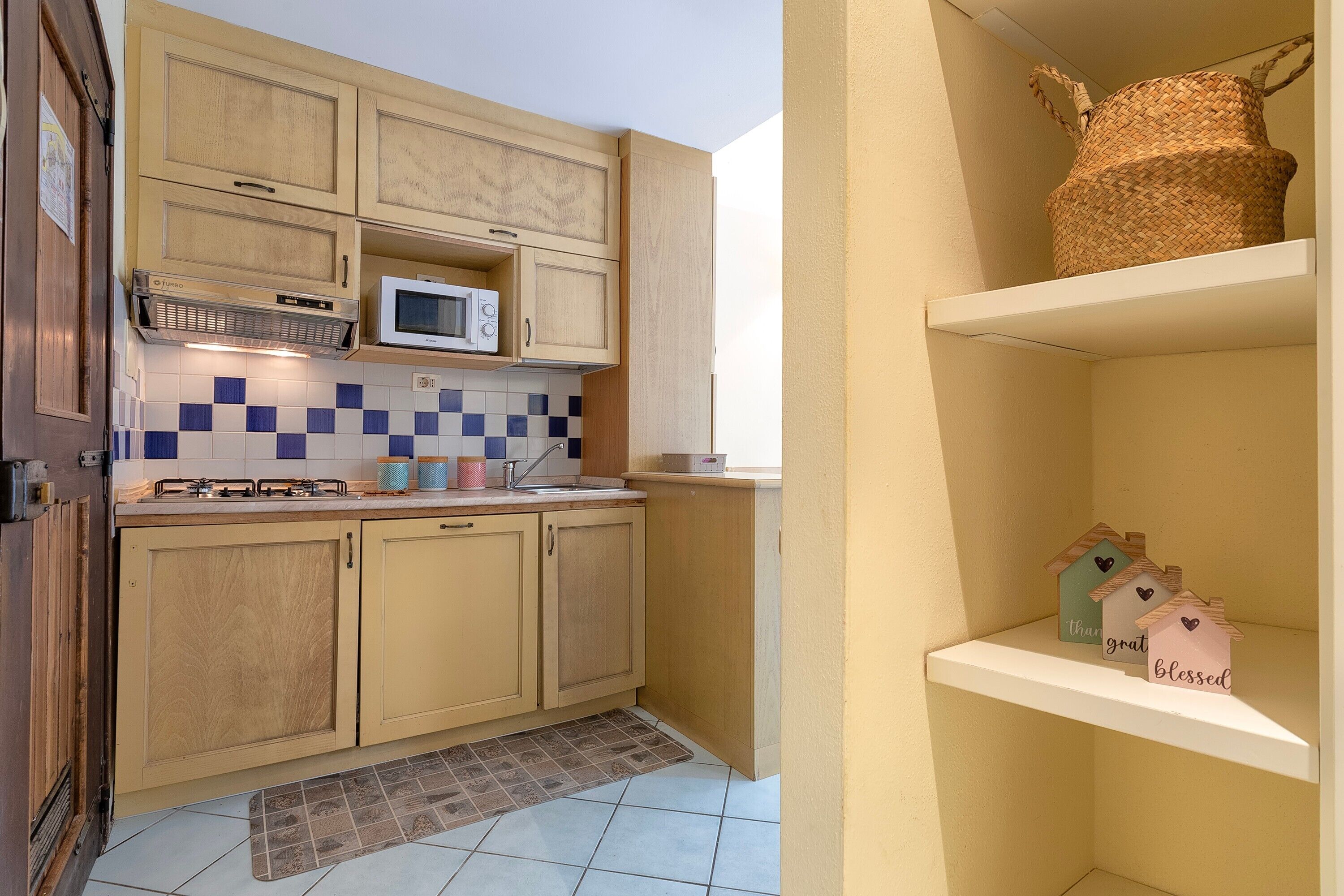 A kitchen with wooden cabinets, a microwave, and a tiled backsplash.