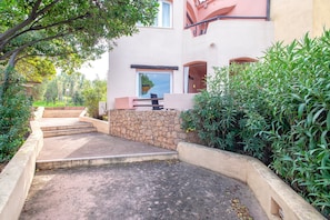 A building with a stone wall, a staircase, and a small outdoor seating area.