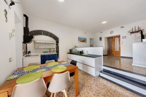 A compact kitchen with a built-in oven, a dining area with a table and chairs, and a staircase leading to an upper level.