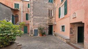 A narrow alleyway with stone pavement, potted plants, and traditional buildings with green shutters. - Apartment 'Profumo Di Salsedine' with Sea View, Wi-Fi and Air Conditioning (Bonassola)