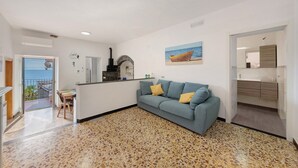 A living area with a sofa, a dining table, a kitchen island, and a view of the sea. - Apartment 'Profumo Di Salsedine' with Sea View, Wi-Fi and Air Conditioning (Bonassola)