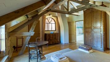 A rustic attic bedroom with exposed wooden beams, a wooden dining table, and a large wardrobe.