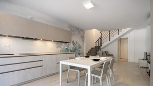 A modern kitchen with a dining area, a staircase, and a minimalist design. - Apartment 'Berton' with Private Terrace, Balcony, and Air Conditioning (Jesolo)