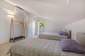 A bedroom with two beds, a wooden drying rack, and an air conditioning unit. - Apartment 'Berton' with Private Terrace, Balcony, and Air Conditioning (Jesolo)