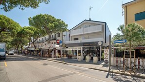A street view with a bakery bistro, a white building with balconies, and a bicycle parked on the sidewalk. - Apartment 'Berton' with Private Terrace, Balcony, and Air Conditioning (Jesolo)