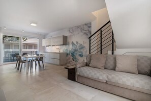 Una sala de estar moderna con sofá, mesa de comedor, sillas y una zona de cocina.