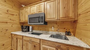A kitchen with wooden cabinets, a microwave, a coffee maker, and a sink. - Pam's Treehouse Cabin #1-A favorite treehouse right on a creek! (Hot Springs)