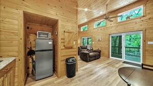A wooden cabin interior with a kitchen, dining area, and a sofa. - Pam's Treehouse Cabin #1-A favorite treehouse right on a creek! (Hot Springs)