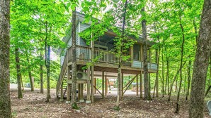 A wooden cabin with a deck, surrounded by trees. - Pam's Treehouse Cabin #1-A favorite treehouse right on a creek! (Hot Springs)