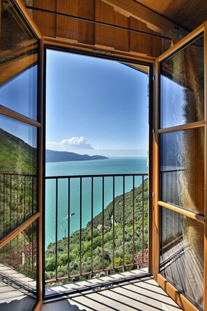 Un balcon offrant une vue sur un lac, des montagnes et un ciel dégagé.