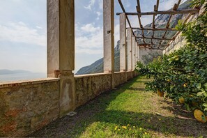 Mural de pedra com pérgola de madeira e vista para uma paisagem montanhosa.