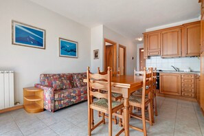 Un coin repas avec une table et des chaises en bois, un canapé à motifs et des meubles de rangement en bois dans une cuisine.