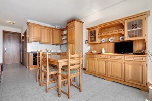 Una cucina con mobili in legno, un tavolo da pranzo con sedie e un televisore.