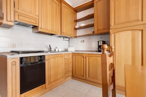 Cucina con mobili in legno, forno integrato e piano di lavoro.