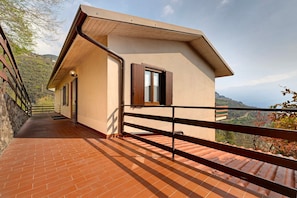 Un bâtiment moderne doté d’un balcon, offrant une vue sur la campagne et possédant un mur en pierre sur l’un de ses côtés.