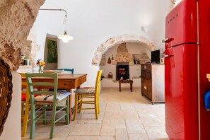 A stone archway leading to a kitchen with a red refrigerator, wooden dining table, and chairs. - Trullo 'Di Serena' with Private Terrace, Wi-Fi and Air Conditioning (Ceglie Messapica)