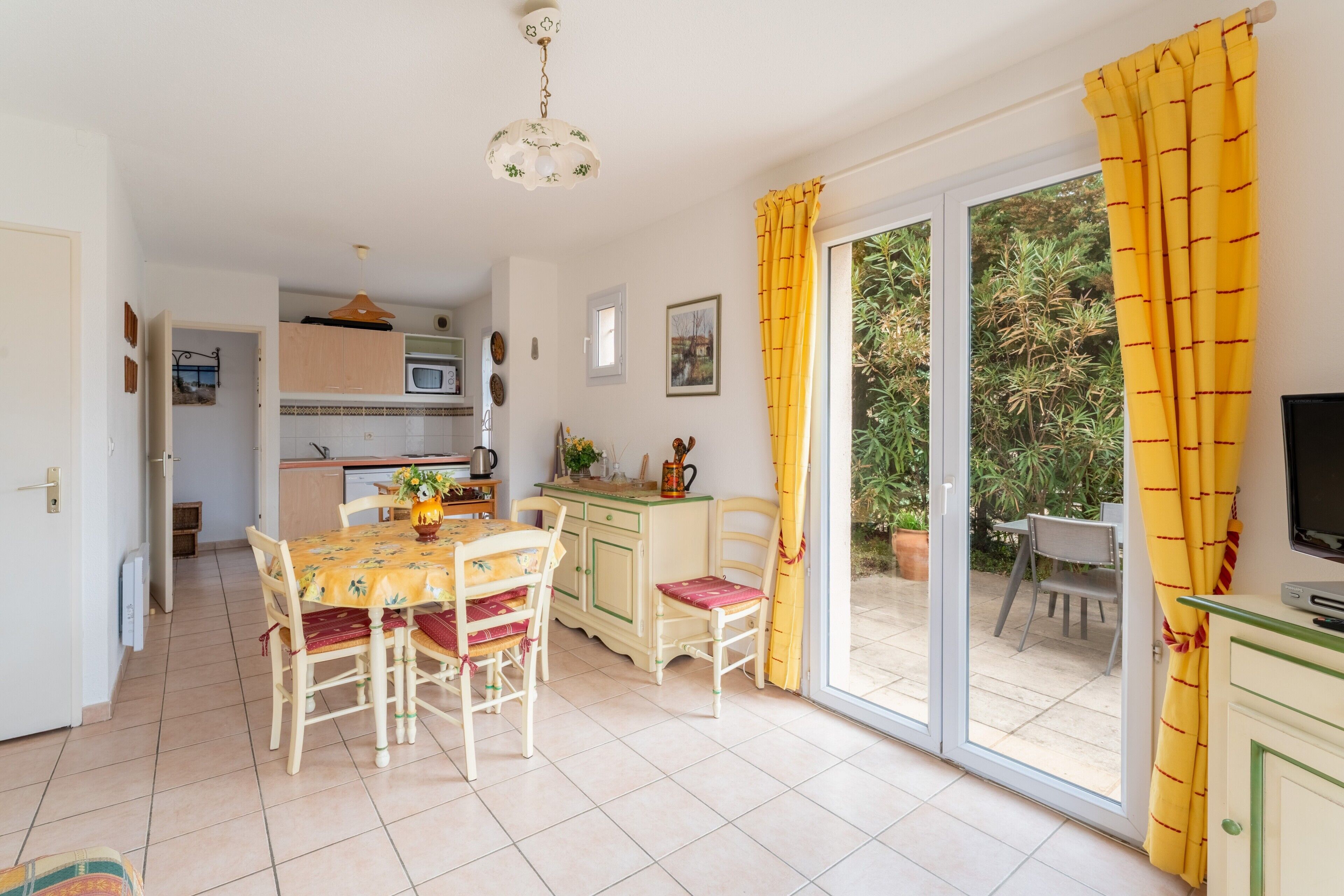 A kitchen with a dining table and chairs, a television, and a sliding glass door to an outdoor area.
