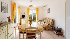 A dining area with a table, chairs, a vase of flowers, a television, and a sofa. - Air-conditioned villa with pool in Vaison-la-Romaine, in the heart of Provence (Vaison-la-Romaine)