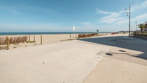 Un paseo marítimo bordeando la playa que conduce al océano, con cielo despejado.