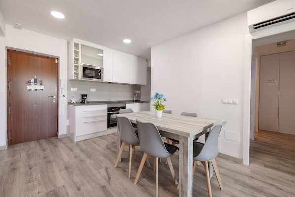 A modern kitchen with white cabinets, a wooden dining table, and grey chairs.