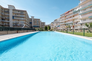 A swimming pool with a clear blue water surface, surrounded by multi-story residential buildings with balconies.