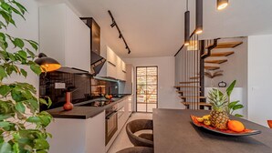 A modern kitchen with a central island, a dining area with a fruit bowl, and a staircase with a wooden finish. - 2 bedroom amazing home in Vela Luka (Vela Luka)