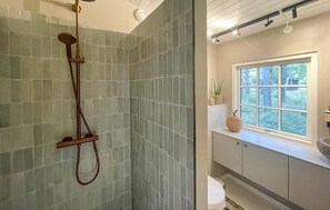 Enjoy a contemporary bathroom experience with a sleek shower, large window, and minimalist design.